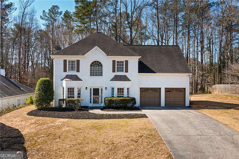 colonial house with an attached garage, a front yard, and concrete driveway