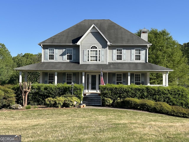 view of front of property featuring a front yard, covered porch, and a chimney