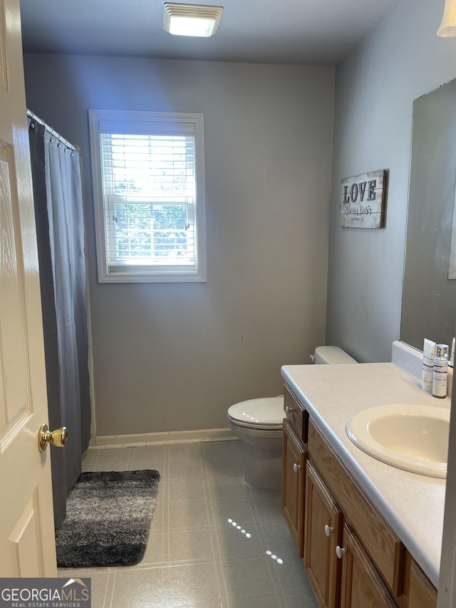 full bath featuring toilet, a shower with curtain, vanity, and baseboards