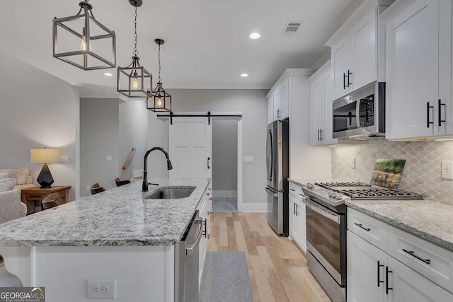 2710 Sandy Irwin Ct SW, Marietta, GA 30064 - kitchen with a barn door, a sink, light wood-type flooring, stainless steel appliances, and visible vents
