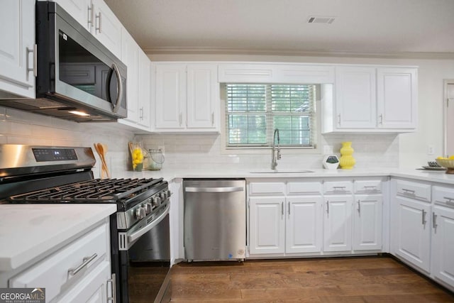 kitchen featuring white cabinets, decorative backsplash, stainless steel appliances, and a sink