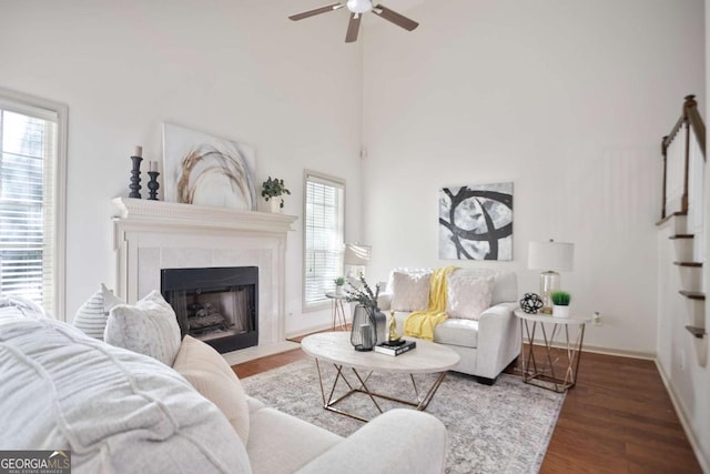living area with baseboards, a ceiling fan, wood finished floors, and a tile fireplace