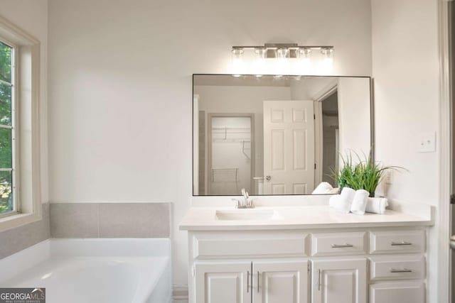 full bath featuring a bath, vanity, and a spacious closet