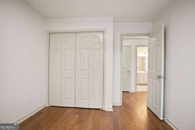 unfurnished bedroom with wood finished floors, a closet, and baseboards