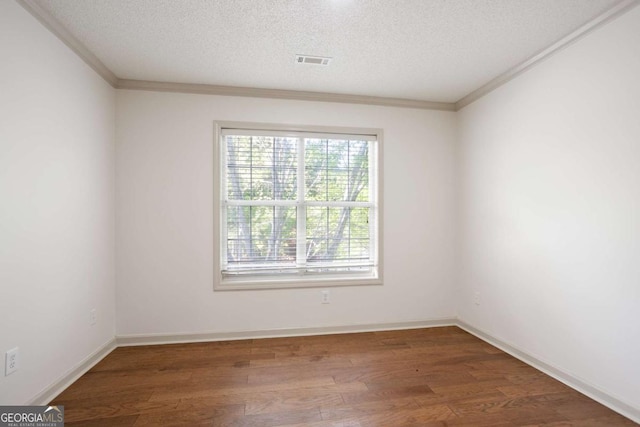 spare room featuring a textured ceiling, wood finished floors, visible vents, and crown molding