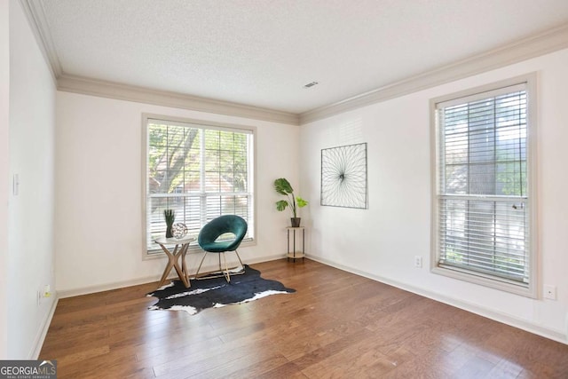 workout room with baseboards, ornamental molding, wood finished floors, and visible vents