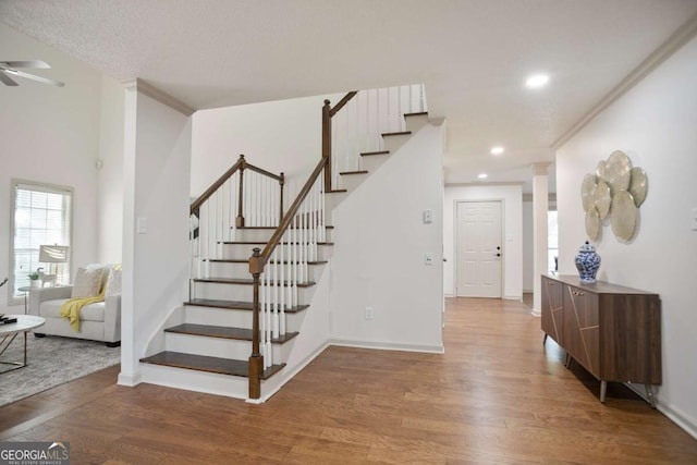 staircase featuring baseboards, a ceiling fan, and wood finished floors