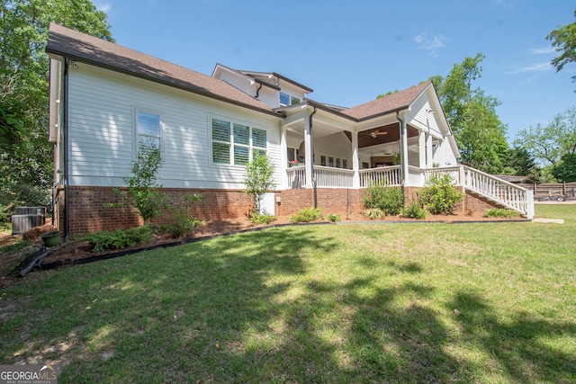 exterior space with central AC unit, a ceiling fan, and a yard