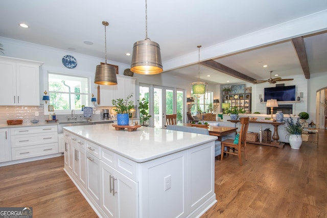 kitchen featuring a sink, a fireplace, ceiling fan, light countertops, and open floor plan
