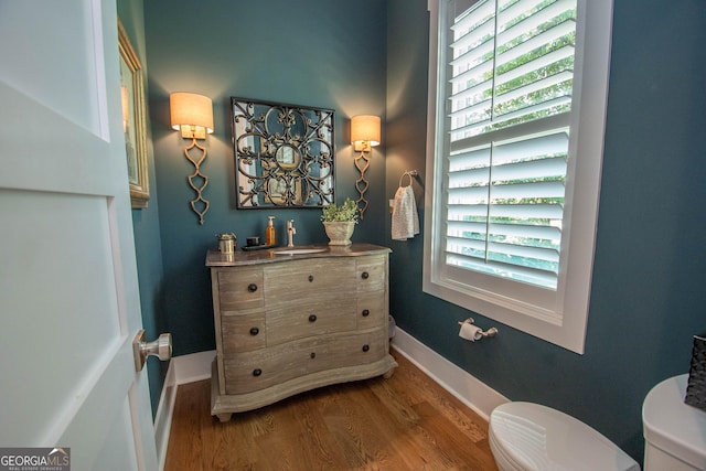 bathroom with wood finished floors, toilet, vanity, and baseboards