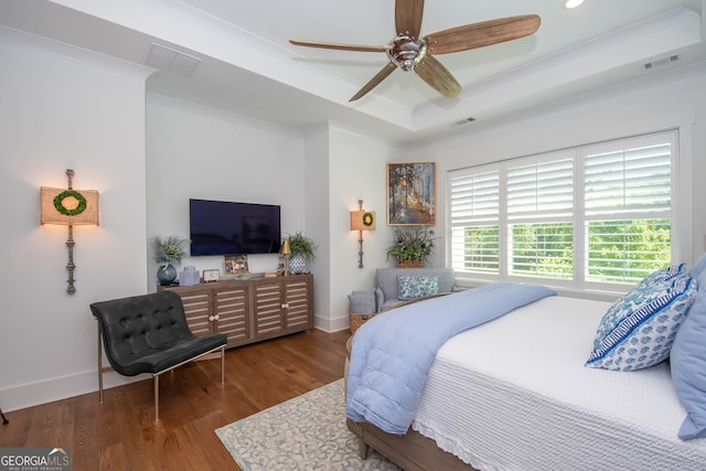 bedroom with ornamental molding, baseboards, wood finished floors, and a tray ceiling