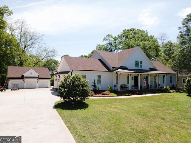 view of front of property featuring a porch, a front lawn, a detached garage, and an outbuilding