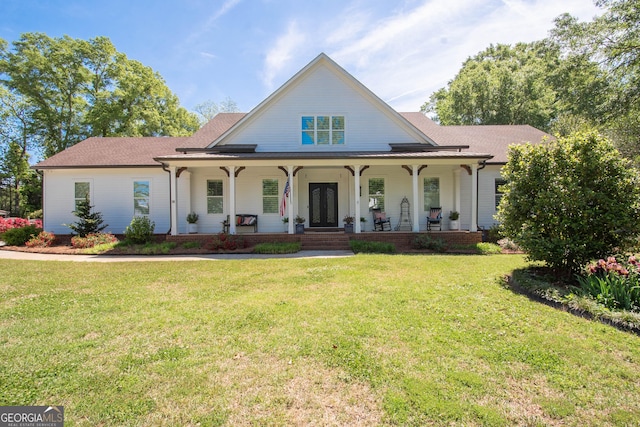 view of front of property featuring a front lawn, french doors, a shingled roof, and covered porch