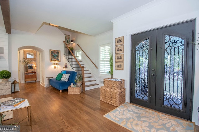 foyer entrance with wood finished floors, arched walkways, stairs, and french doors