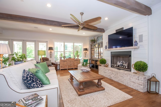 living room with recessed lighting, beam ceiling, a brick fireplace, a ceiling fan, and wood finished floors