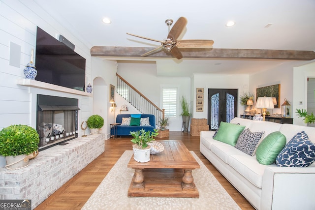 living room with a fireplace, stairway, recessed lighting, and beamed ceiling