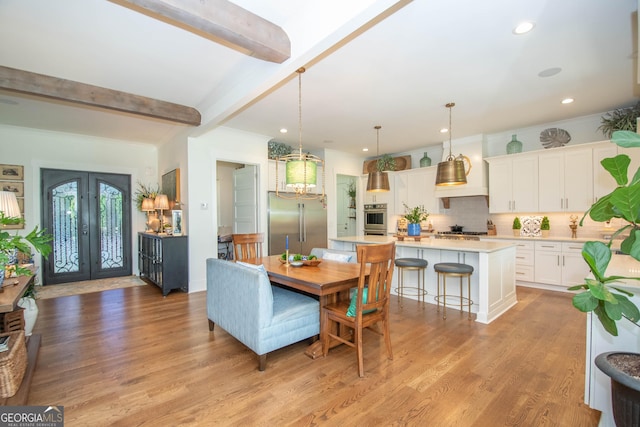 dining area featuring light wood finished floors, recessed lighting, beam ceiling, and french doors