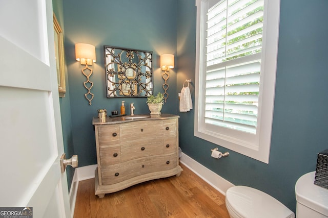 bathroom featuring baseboards, wood finished floors, toilet, and vanity