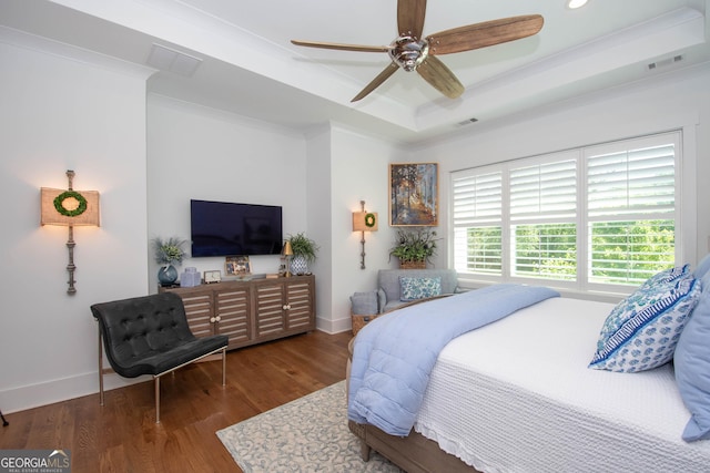 bedroom featuring wood finished floors, ornamental molding, a tray ceiling, and baseboards
