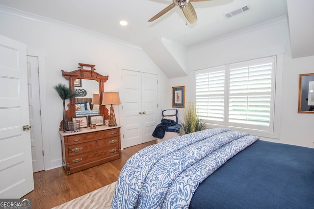 bedroom with crown molding, a closet, visible vents, and wood finished floors