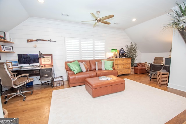 living room with wooden walls, a ceiling fan, visible vents, vaulted ceiling, and wood finished floors