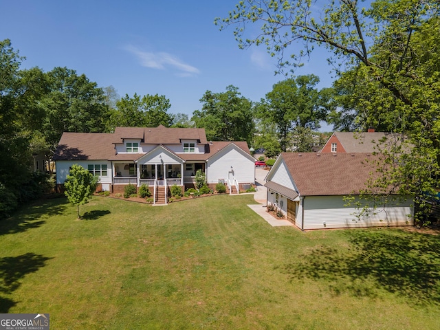 rear view of property featuring covered porch, a yard, a shingled roof, and a garage