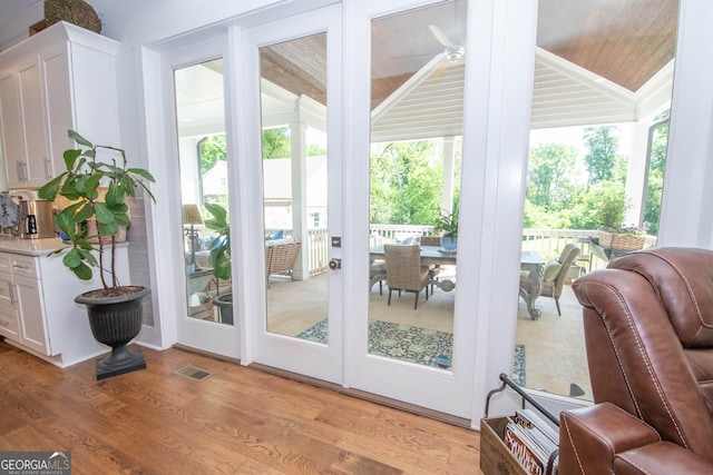 doorway featuring visible vents, light wood-style floors, lofted ceiling, and wooden ceiling