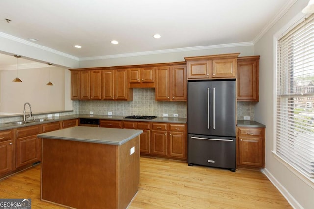 kitchen featuring high quality fridge, brown cabinets, light wood-style flooring, and a sink