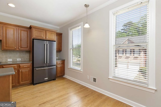 kitchen featuring brown cabinets, light wood finished floors, high end fridge, and tasteful backsplash