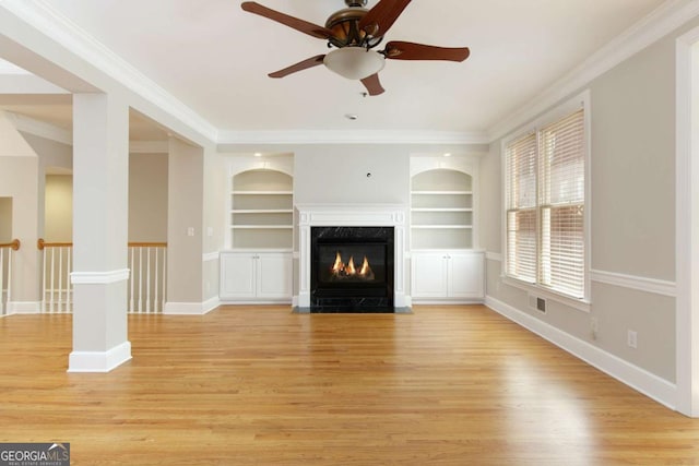 unfurnished living room featuring a ceiling fan, light wood finished floors, visible vents, built in shelves, and a high end fireplace