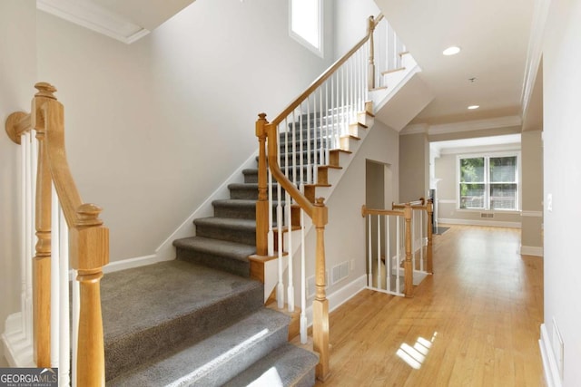 stairs featuring crown molding, visible vents, wood finished floors, and baseboards