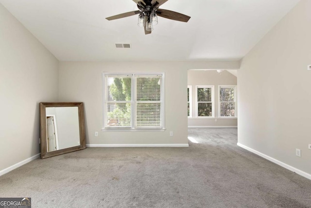 carpeted spare room featuring visible vents, baseboards, and ceiling fan