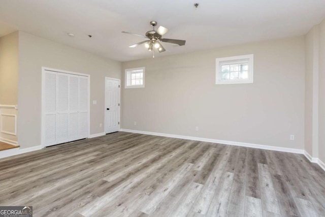 interior space with ceiling fan, baseboards, a closet, and wood finished floors