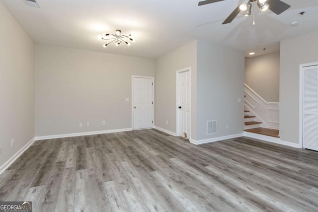 empty room featuring baseboards, ceiling fan, visible vents, stairs, and wood finished floors