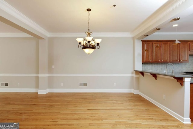 kitchen featuring a breakfast bar, an inviting chandelier, visible vents, and light wood-style flooring