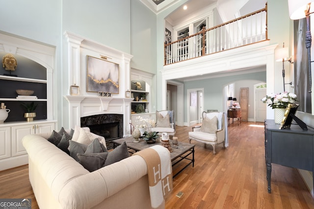 3190 Shumard Way, Marietta, GA 30064 - living room featuring arched walkways, baseboards, a towering ceiling, built in shelves, and light wood-style floors