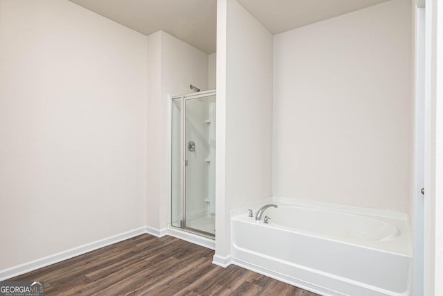 bathroom featuring a bath, baseboards, wood finished floors, and a shower stall