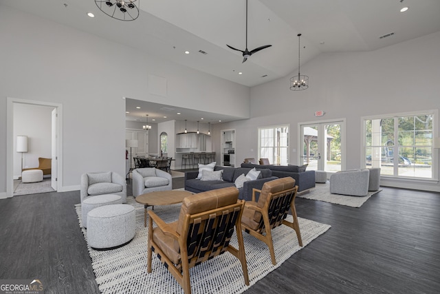 living room featuring high vaulted ceiling, a notable chandelier, visible vents, and dark wood-style floors