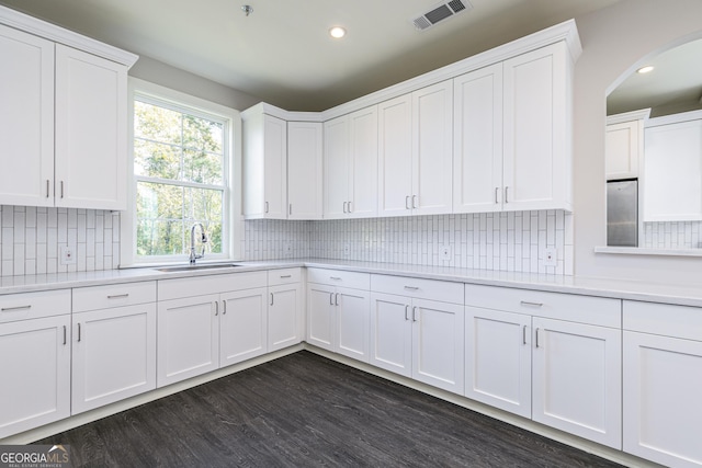 kitchen featuring arched walkways, visible vents, light countertops, and a sink