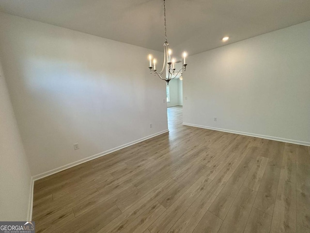 unfurnished dining area with baseboards, wood finished floors, and a notable chandelier
