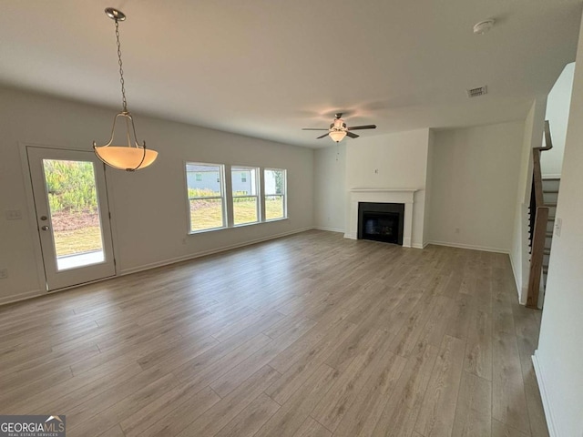 unfurnished living room featuring light wood-style flooring, baseboards, visible vents, ceiling fan, and a fireplace
