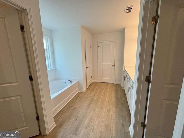 full bathroom featuring a garden tub, wood finished floors, vanity, baseboards, and visible vents