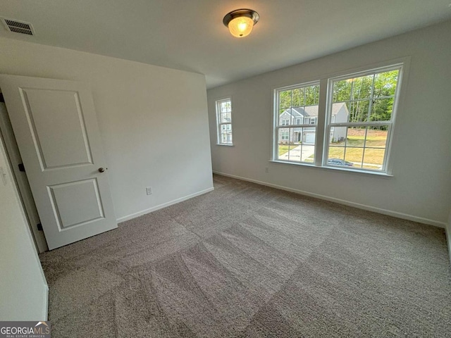 carpeted empty room with visible vents and baseboards
