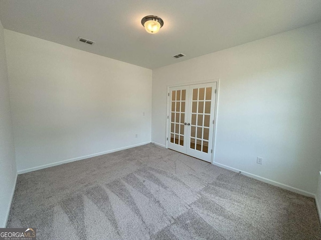 carpeted empty room featuring visible vents, baseboards, and french doors