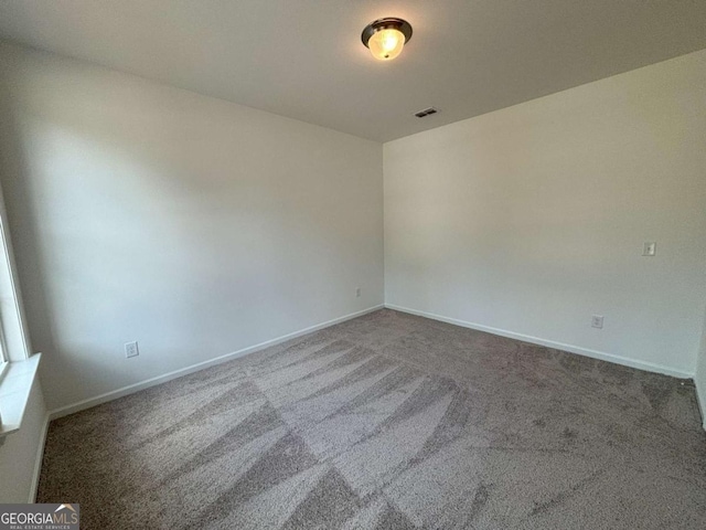 carpeted spare room featuring baseboards and visible vents