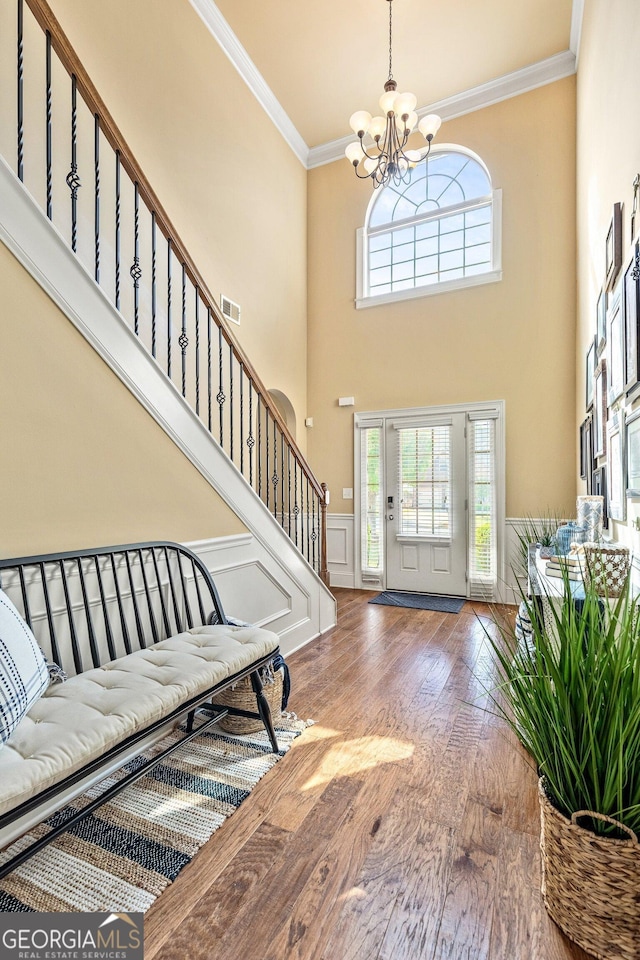 living room featuring ceiling fan, a fireplace, crown molding, a decorative wall, and a wainscoted wall