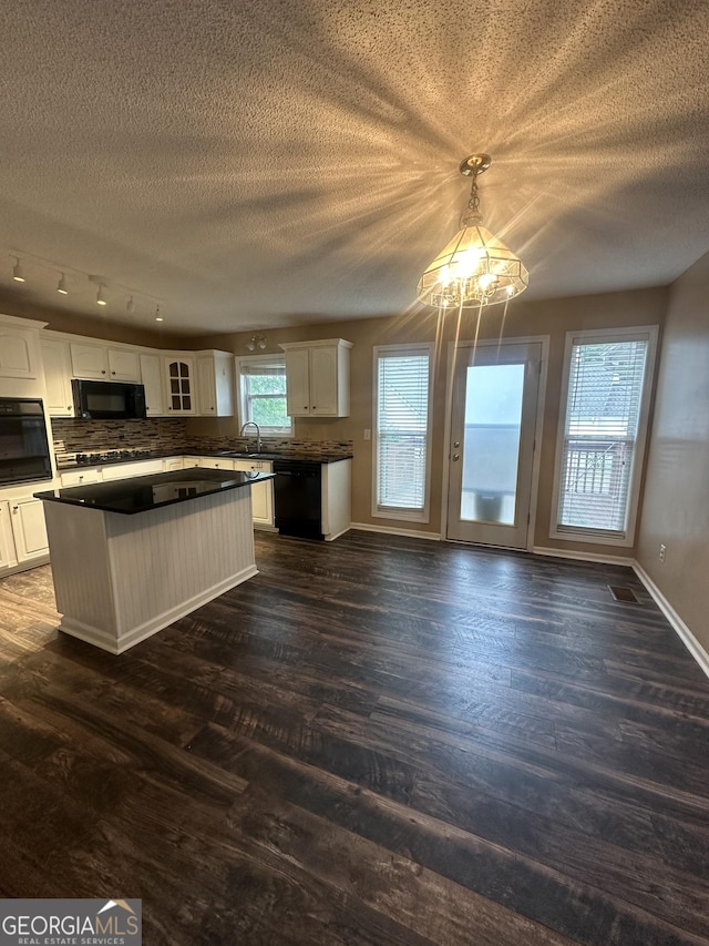 kitchen with black appliances, a chandelier, a textured ceiling, dark countertops, and tasteful backsplash