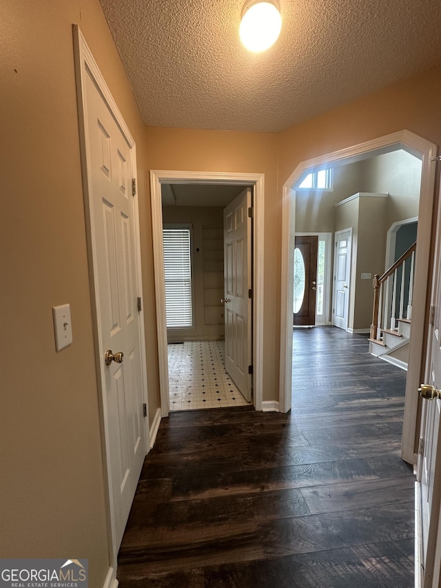 hall with dark wood finished floors, stairway, a textured ceiling, and baseboards