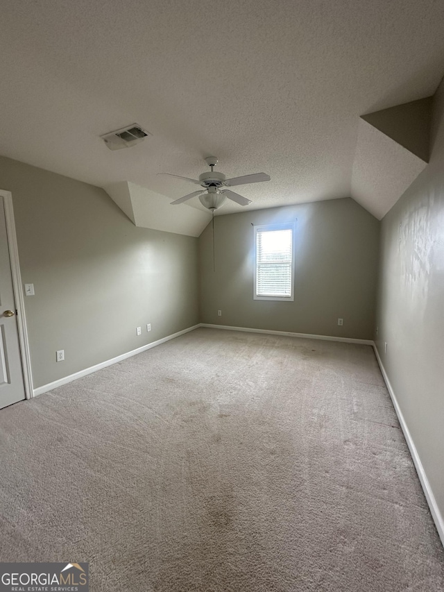 additional living space featuring lofted ceiling, ceiling fan, carpet, a textured ceiling, and baseboards