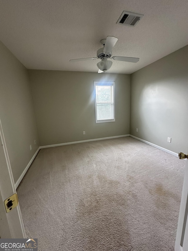 empty room featuring a ceiling fan, baseboards, a textured ceiling, and carpet